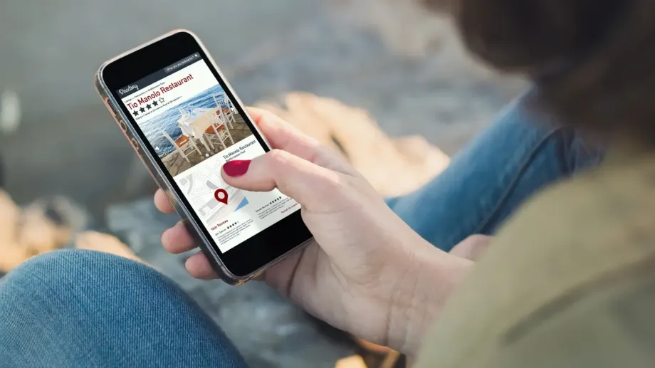 Woman is holding a mobile device and reviewing a business listing.