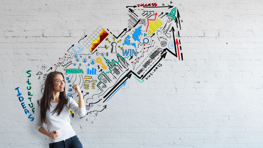 Fun graphic on a wall indicating success through words. There's a smiling woman posing in front.