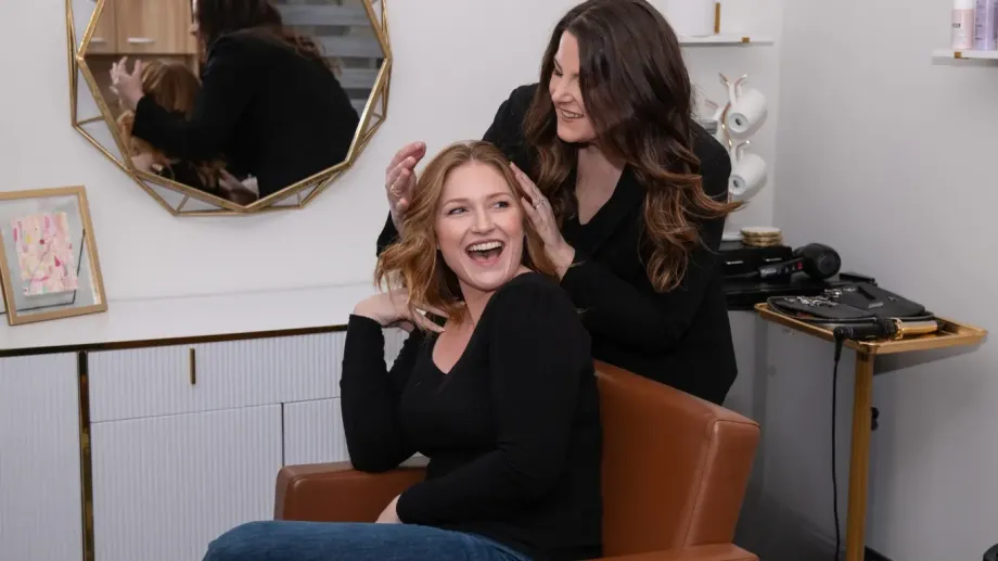 Hair stylist and customer smiling about successful hair style.