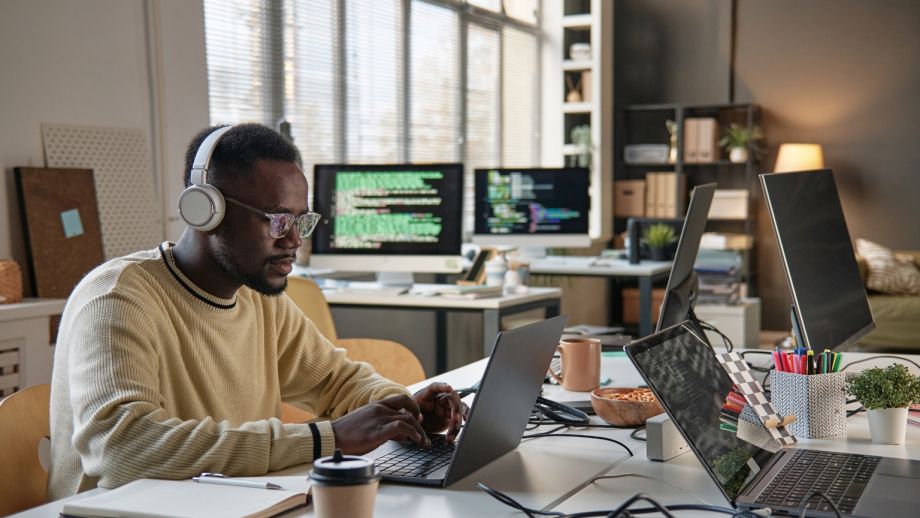 Tech professional working at a computer in an office with a lot of other computers.