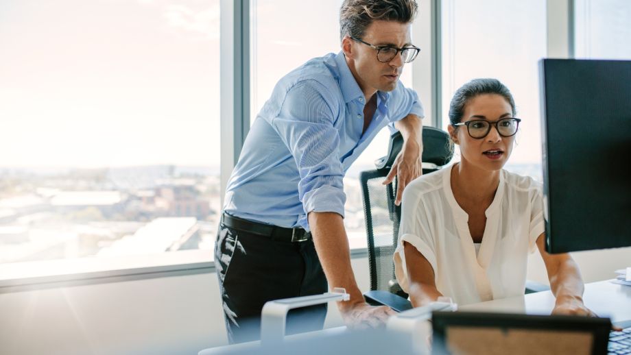 Tech professionals working together at a desk and looking at a computer.