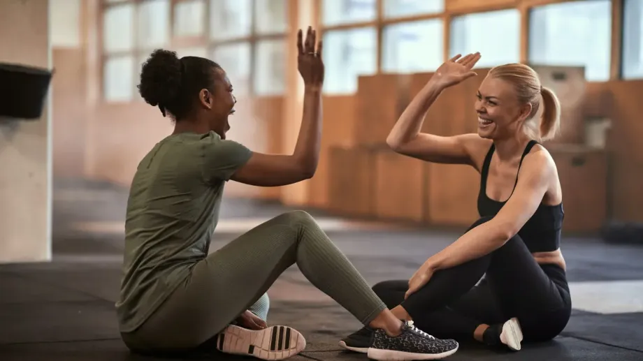 Friends giving each other high fives. They are sitting on the floor in a gym.